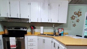 Eine Küche mit weißen Schränken, einem Edelstahlbackofen und Holzboden.