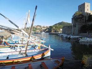 Ein Hafen mit angestoßenen Booten, eine Burg auf einem Hügel und eine Stadt im Hintergrund.