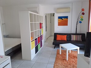A modern living room with a white sofa, a small white table, and a colorful storage unit. - Panoramic view with a swimming pool: nestled between the sea and the mountains, in a quiet location. (Laroque-des-Albères)