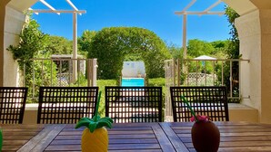 Eine Terrasse im Freien mit einem Holztisch, zwei Stühlen, einer gelben Ananas-Dekoration und einer braunen Vase.