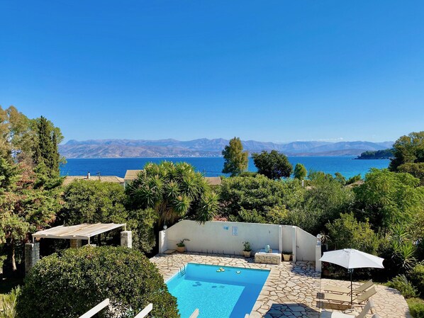 A pool area with a view of the sea and mountains.
