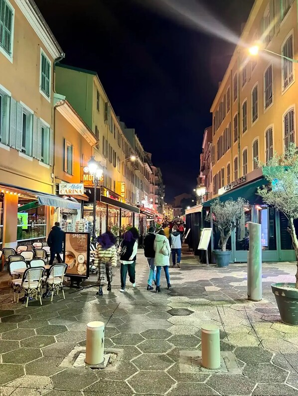 A nighttime street scene with people walking, outdoor seating, and illuminated storefronts. - Stunning apartment in the Gold Square of Nice! (Nice)