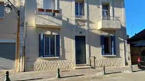 Un edificio de dos plantas con fachada de piedra, múltiples ventanas y un balcón con mobiliario exterior.