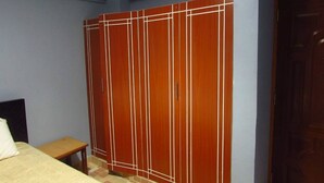 A bedroom with a bed, a wooden wardrobe, and a small table. - Home away from home (Nyeri)