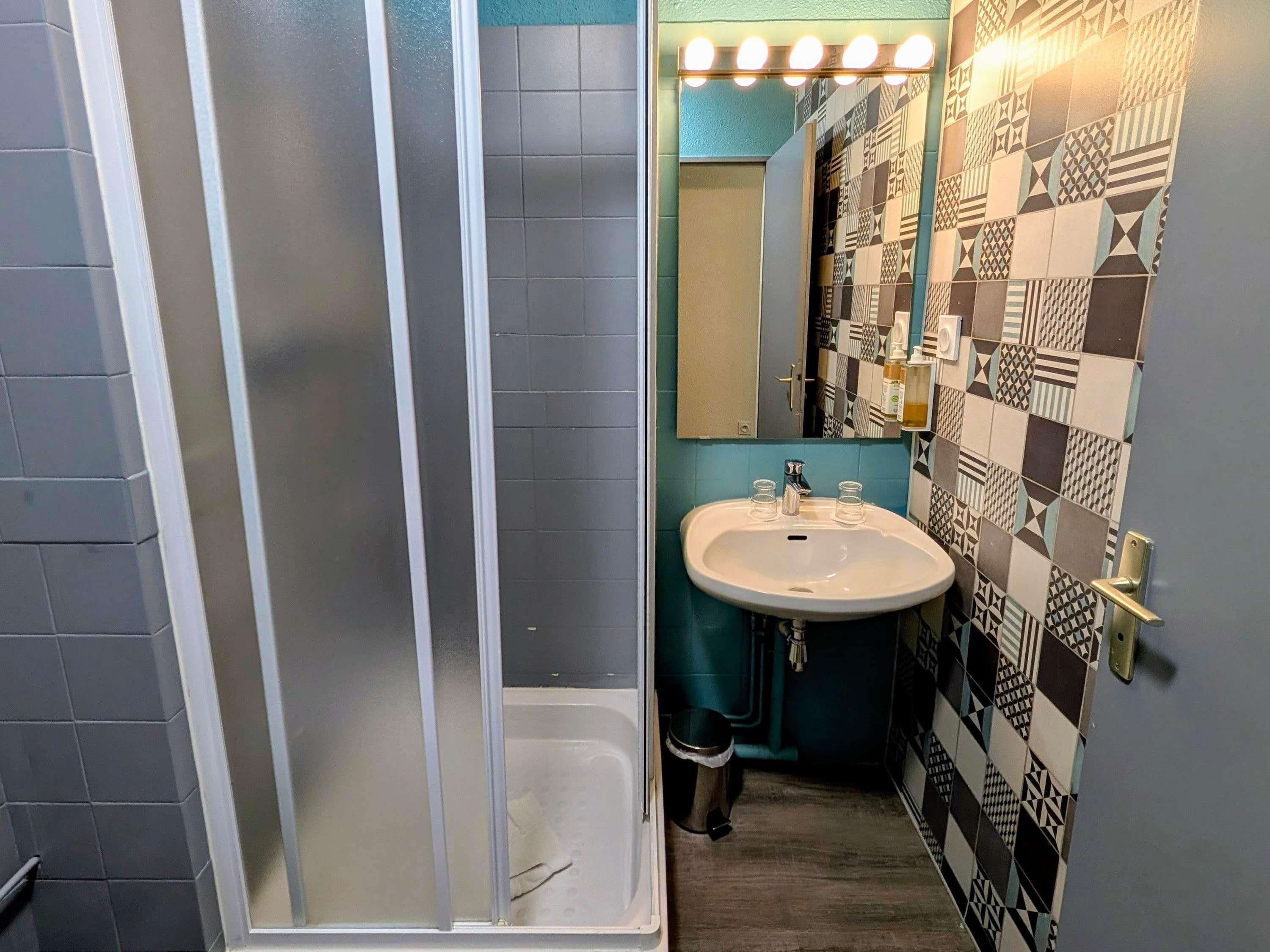 A bathroom with a shower, sink, and a mirror.