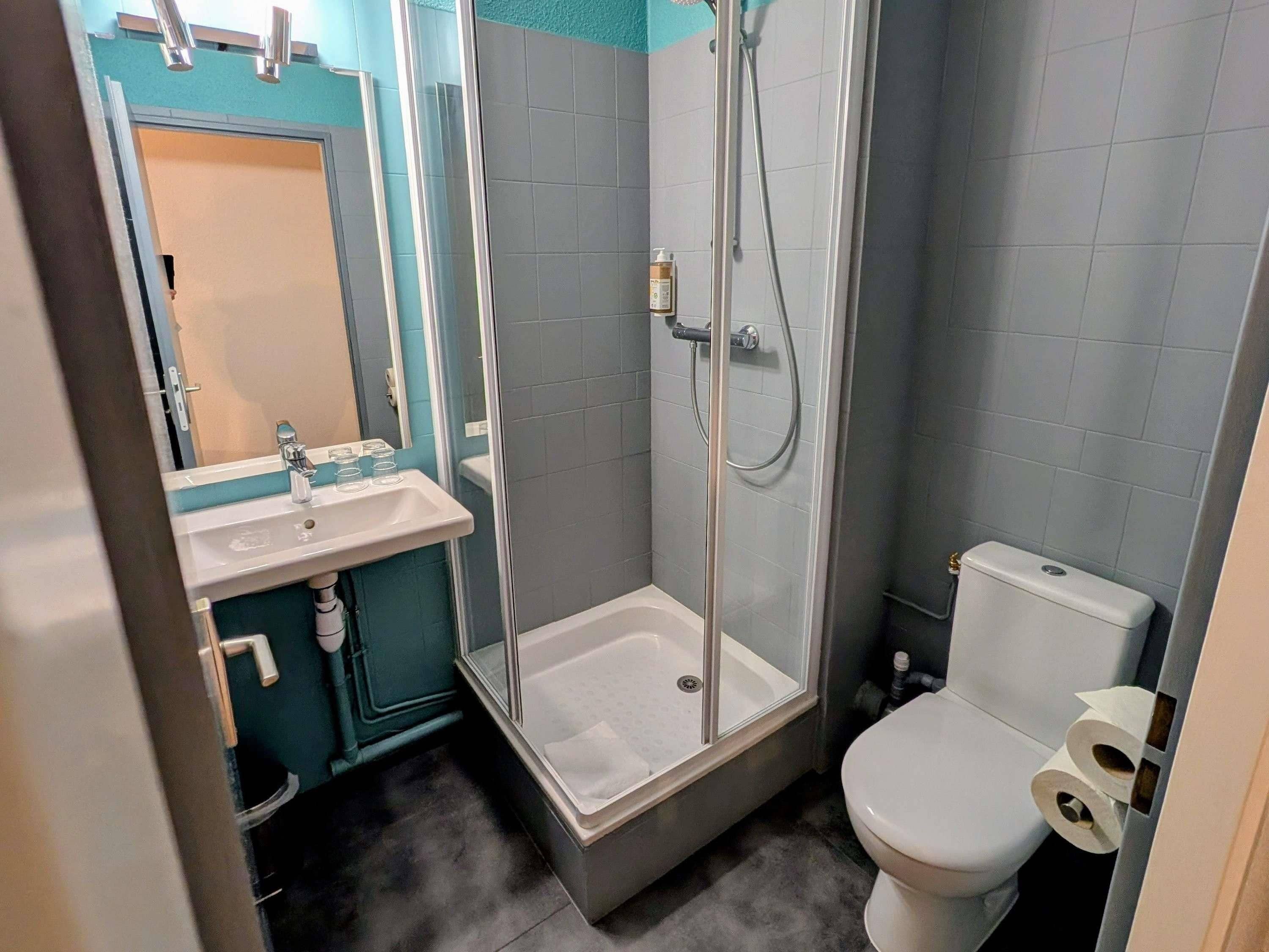 Un baño con ducha de vidrio, un lavabo con espejo y un inodoro.