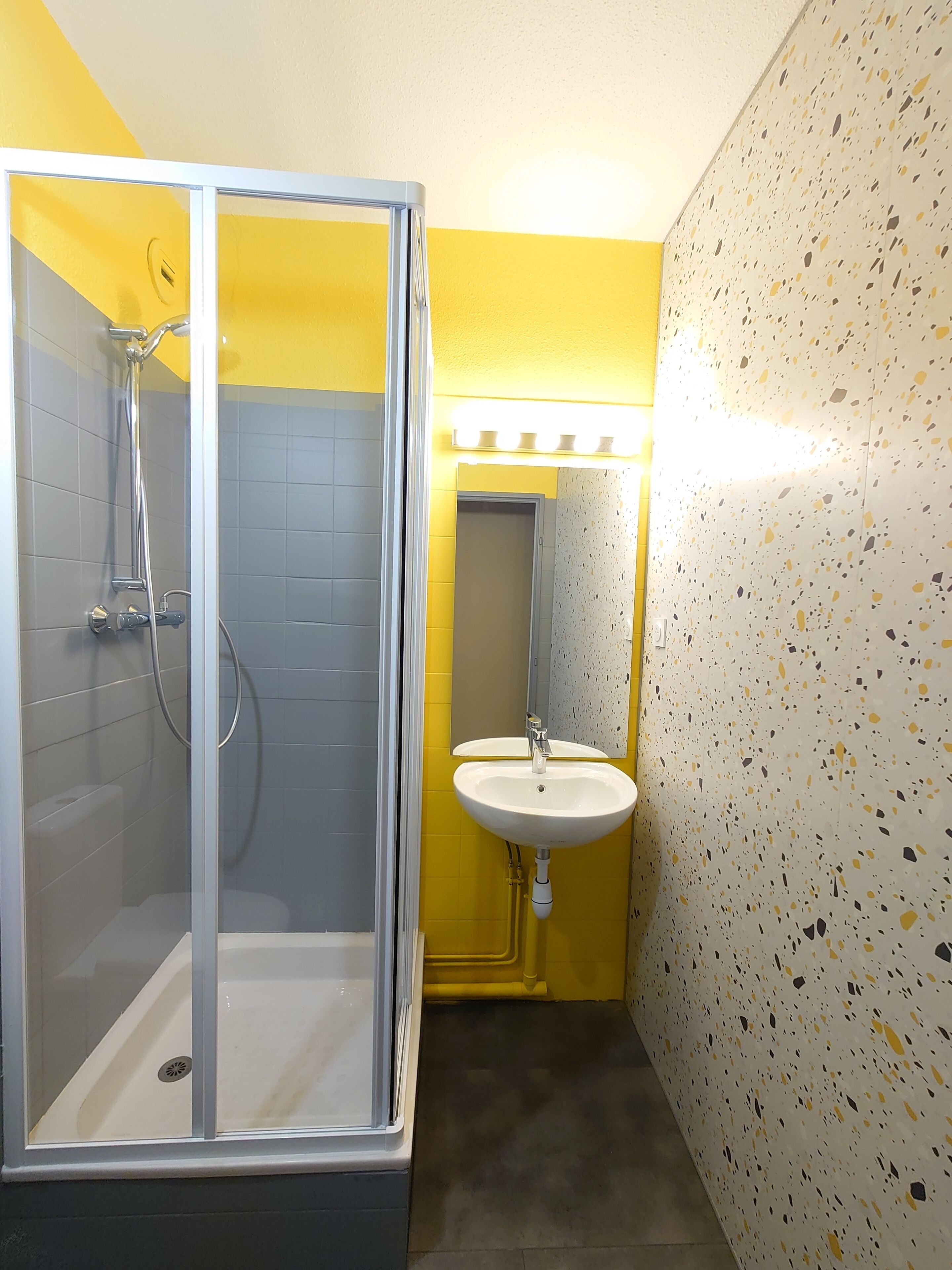 Ein Badezimmer mit Duschkabine, Waschbecken und Spiegel.