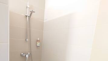 A small, modern shower area with a handheld showerhead and a fixed showerhead, a handheld soap dispenser, and a single white tile wall.