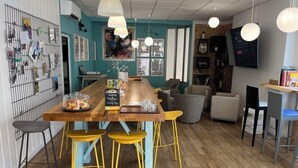 A cozy café with a wooden table, yellow stools, and a teal accent wall. - Greet Hotel Grenoble Centre Gare (Grenoble)