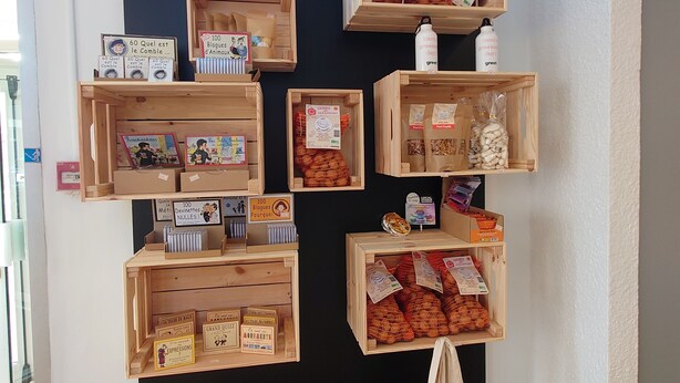 A boutique with wooden display shelves containing various products like candles, soaps, and snacks. - Greet Hotel Grenoble Centre Gare (Grenoble)