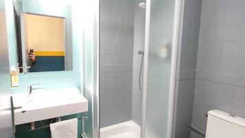 A modern bathroom with a glass-enclosed shower, a white sink, and a toilet.