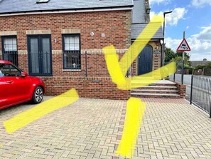 A red car parked in front of a brick building with a yellow line on the pavement.