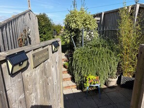 Ein hölzernes Tor mit einem Schild, auf dem 'The Old Chapel Garden' steht, und einer solarbetriebenen Lampe.