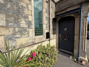 A stone building with a black door, a window with a grid pattern, and a sign that reads 'The Old Chapel'. - 1902 chapel. Family friendly. Parking & garden.  (Sandown)