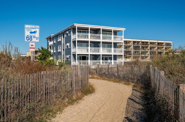 A beachfront building with multiple balconies and a sandy path leading to it. - Direct Oceanfront Top Floor | Large Balcony + Stunning Views (Ocean City)