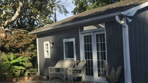 Une maison de plain-pied dotée d’un porche couvert, d’une porte-fenêtre coulissante et d’un petit espace extérieur aménagé avec deux chaises.