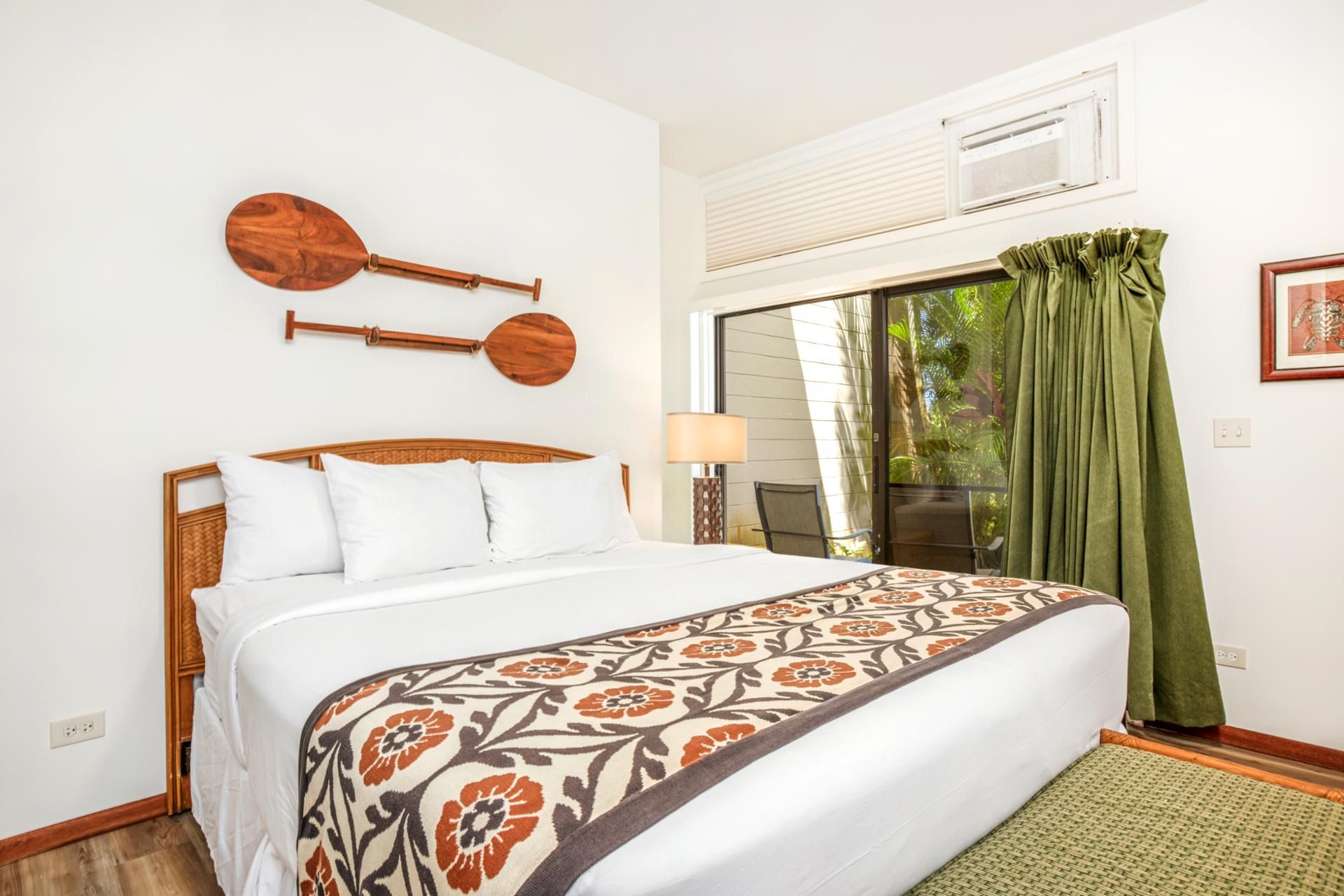 Una camera da letto con un letto, un pannello decorativo in legno, una finestra con tende e vista sul verde circostante.
