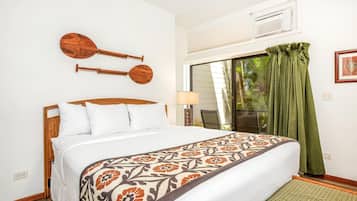 Una camera da letto con un letto, un pannello decorativo in legno, una finestra con tende e vista sul verde circostante.