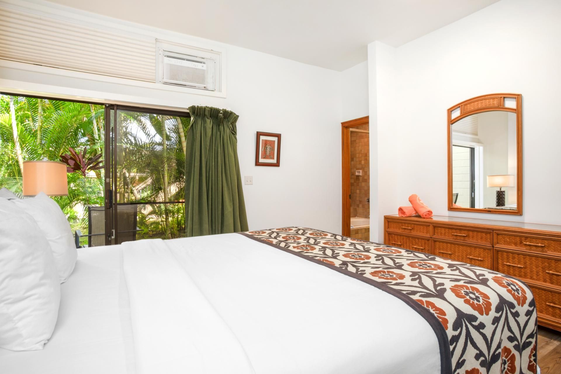 Une chambre d’hôtel avec un lit, une commode, un miroir et une fenêtre avec des rideaux.