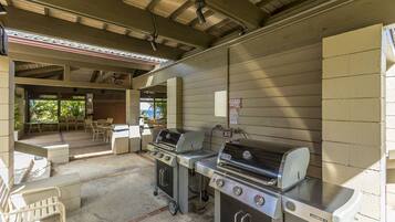 An outdoor patio area with a barbecue grill, a grill cart, and a seating area with chairs and a table.