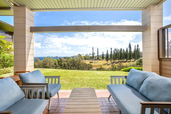 Un patio techado con vistas a un campo de golf y al océano.
