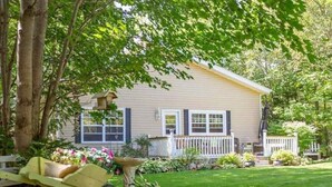 A single-story house with a front porch, surrounded by a well-maintained lawn and various plants. - Gowdas Cottage (New Glasgow)