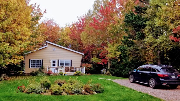 A house with a front porch, a driveway, and a car parked in front. - Gowdas Cottage (New Glasgow)