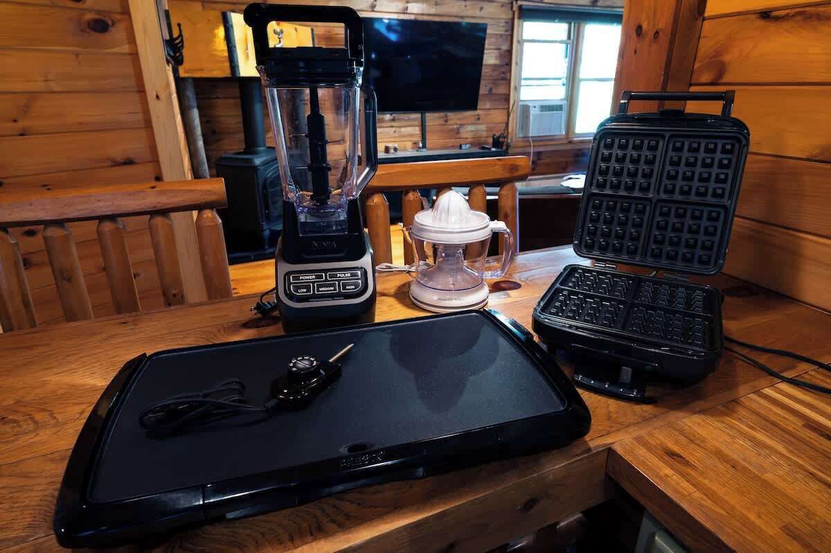 A kitchen counter with a blender, waffle maker, and a tray with a key.
