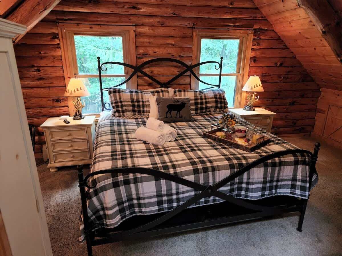 Une chambre confortable avec une couvre-lit à carreaux, un coussin décoratif et une table de chevet avec une lampe.