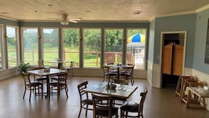 A dining area with multiple tables and chairs, large windows with a view of a backyard, and a ceiling fan. - A place to unwind!! (Kansas)