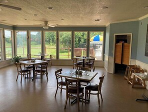 Enjoy meals in this dining area with a high ceiling and large windows offering a view of the outdoors.