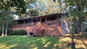 A two-story cabin with a wooden deck and stairs leading to a porch. - A place to unwind!! (Kansas)