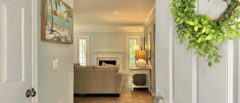 A hallway leading to a living room with a fireplace, a sofa, and a lamp.