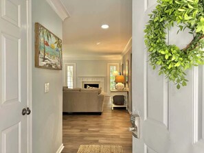 A hallway leading to a living room with a fireplace, a sofa, and a lamp.