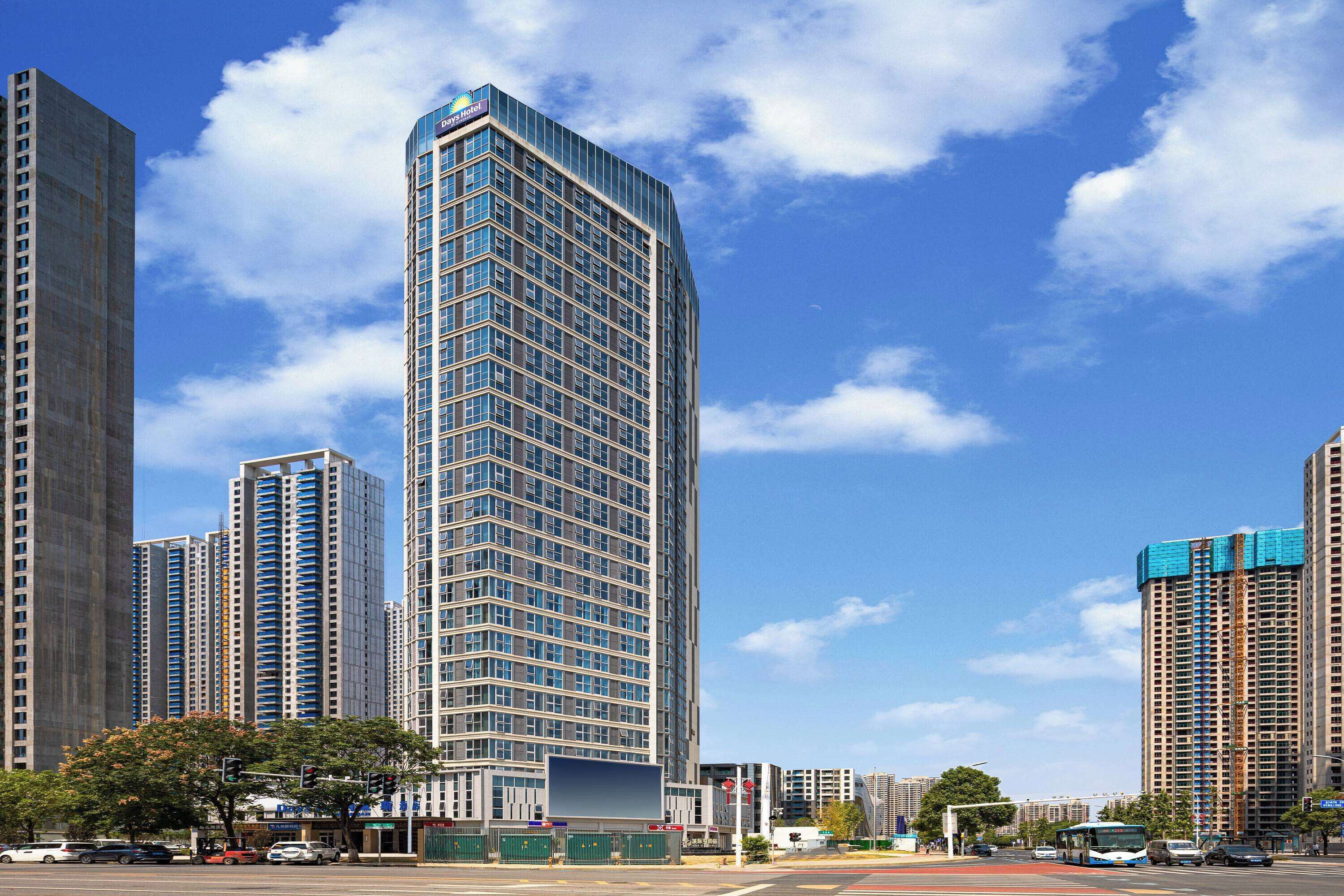 A modern high-rise building with a curved facade, surrounded by other tall buildings and a clear blue sky.