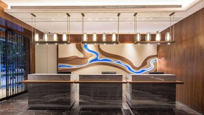 A reception area with three marble counters, a modern light fixture, and a wall mural. - Days Hotel by Wyndham Changsha South (Changsha)