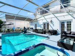 A covered outdoor swimming pool with a sunshade, outdoor seating, and a pergola structure.