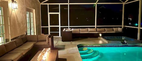 Een buitenzwembad met een jacuzzi, een bank en een tafel.