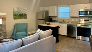 Una cocina moderna con armarios blancos, electrodomésticos de acero inoxidable y una isla central.