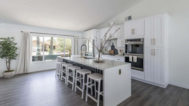 A modern kitchen with a central island, bar stools, white cabinetry, and a large window. - Old Town Fashioned-Pool-Putting Green-BBQ Grill (Scottsdale)