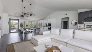 A spacious living room with a white sofa, a coffee table, and a dining area with chairs and a table. - Old Town Fashioned-Pool-Putting Green-BBQ Grill (Scottsdale)