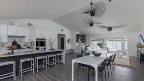 A modern kitchen with white cabinetry, a central island with stools, and pendant lighting. - Old Town Fashioned-Pool-Putting Green-BBQ Grill (Scottsdale)