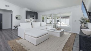 A modern living room with a white sofa, a coffee table, and a TV. - Old Town Fashioned-Pool-Putting Green-BBQ Grill (Scottsdale)
