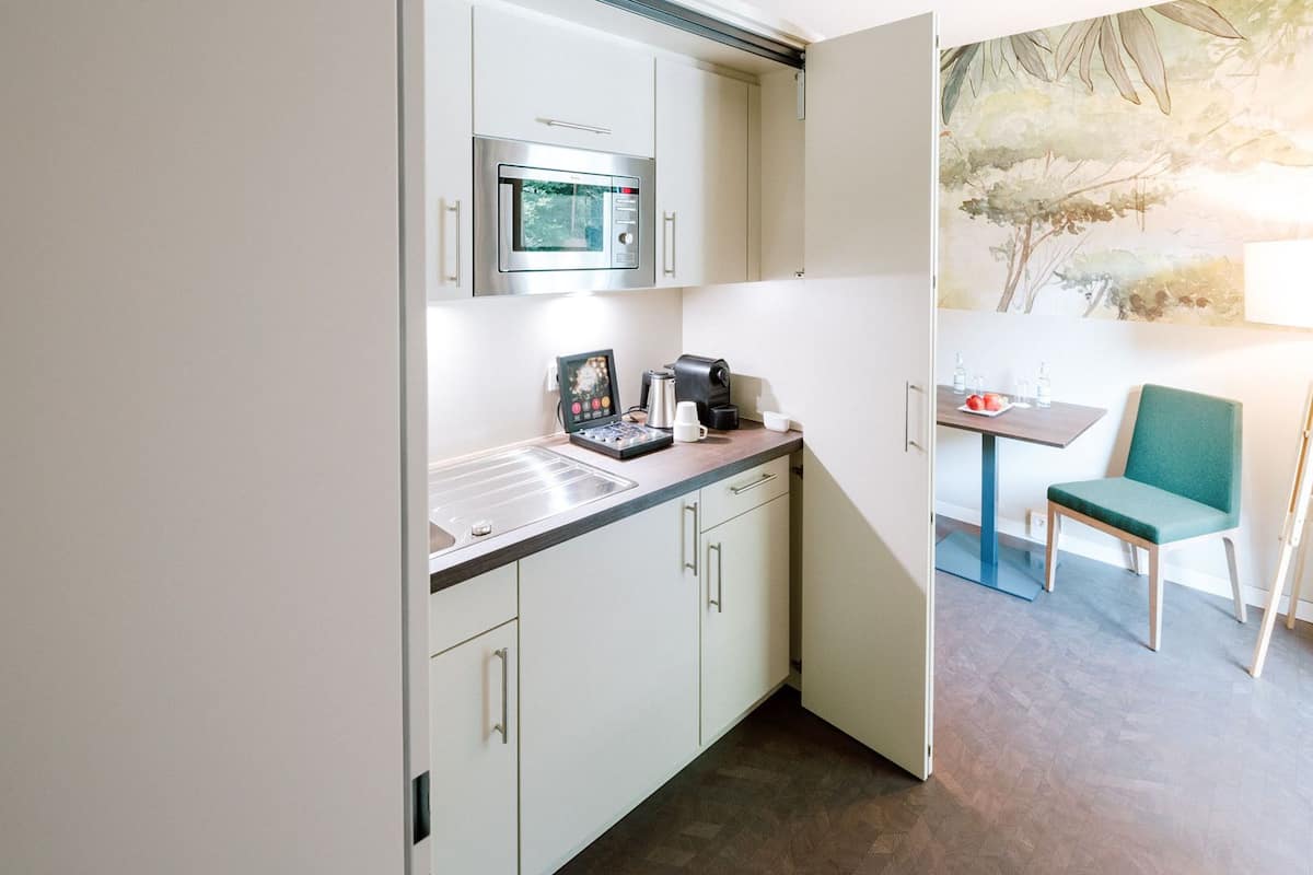 A compact kitchenette with a microwave, coffee maker, and a small table with a chair.