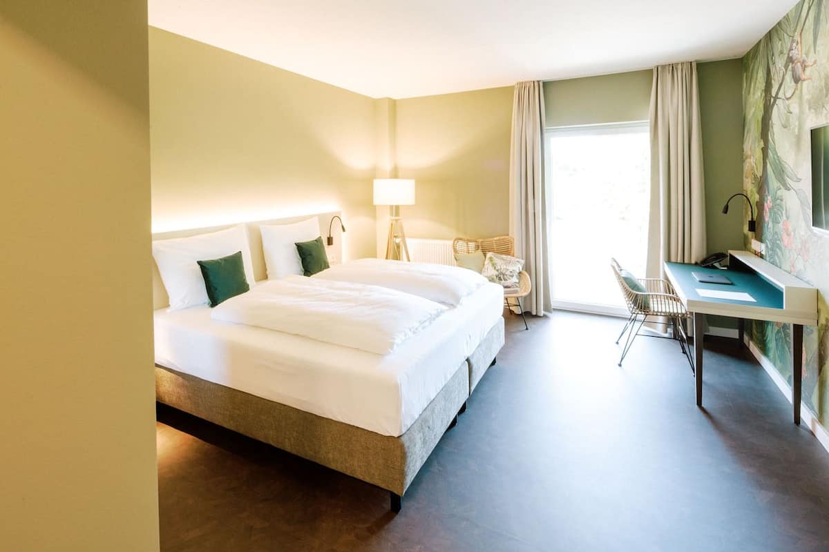 A hotel room with a large bed, a desk, and a chair.