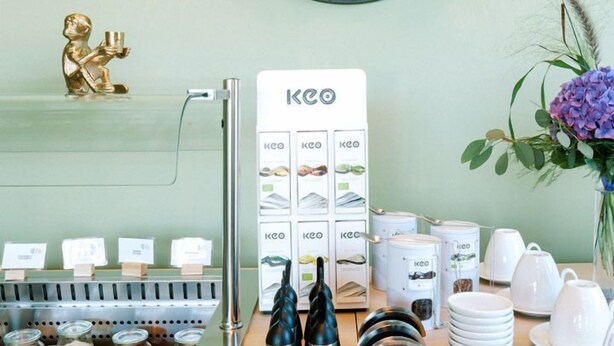 A coffee station with a KEECO display, a small golden statue, and a wall-mounted circular artwork. - Hotel Am Zoo (Neunkirchen)