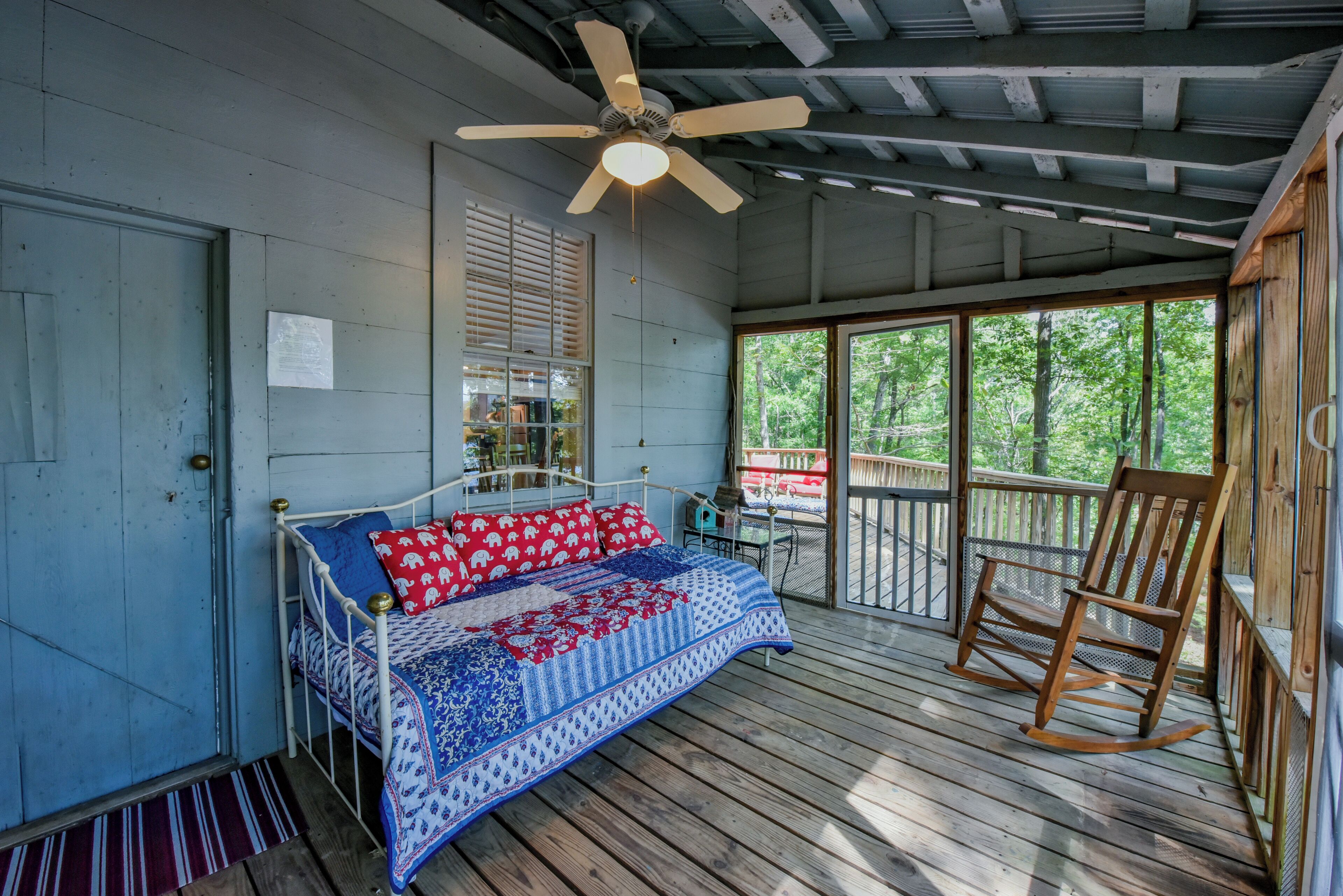 A bedroom with a bed, a ceiling fan, a window, and a wooden rocking chair.