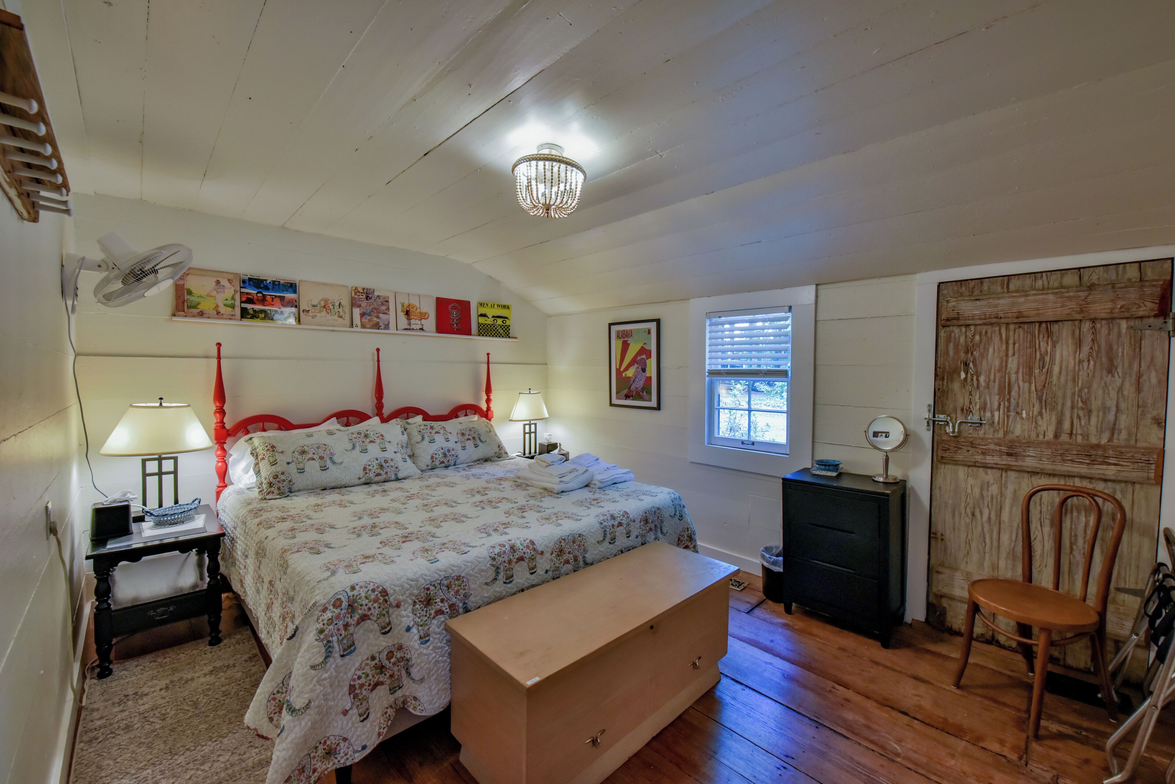 A bedroom with a bed, bedside lamps, a dresser, a chair, and a window with blinds.