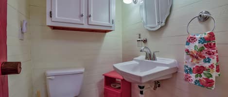 Un baño con inodoro, lavamanos, espejo y mueble.