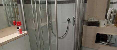 A modern bathroom with a glass-enclosed shower, a white sink, and a toilet.